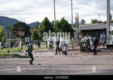 Bogota, Kolumbien. Juni 2021. Ein Demonstrator wirft der kolumbianischen Bereitschaftspolizei (ESMAD) Steine und Debree zu, als die Bewohner von Fontanar - Suba in Bogota, Kolumbien, protestierten und gegen die kolumbianische Bereitschaftspolizei (Escuadron Movil Antidisturbios ESMAD) gegen den Besuch des kolumbianischen Präsidenten Ivan Duque Marquez in einem Park, in dem Bogotas U-Bahn-System gebaut werden soll, zusammenprallten. Inmitten von zwei Monaten regierungsfeindlicher Proteste gegen den Präsidenten Ivan Duque Marquez, Ungleichheiten und Polizeiunruhen während der Proteste am 29. Juni 2021. Kredit: Long Visual Press/Alamy Live Nachrichten Stockfoto