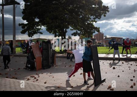 Bogota, Kolumbien. Juni 2021. Ein Demonstrator wirft der kolumbianischen Bereitschaftspolizei (ESMAD) Steine und Debree zu, als die Bewohner von Fontanar - Suba in Bogota, Kolumbien, protestierten und gegen die kolumbianische Bereitschaftspolizei (Escuadron Movil Antidisturbios ESMAD) gegen den Besuch des kolumbianischen Präsidenten Ivan Duque Marquez in einem Park, in dem Bogotas U-Bahn-System gebaut werden soll, zusammenprallten. Inmitten von zwei Monaten regierungsfeindlicher Proteste gegen den Präsidenten Ivan Duque Marquez, Ungleichheiten und Polizeiunruhen während der Proteste am 29. Juni 2021. Kredit: Long Visual Press/Alamy Live Nachrichten Stockfoto