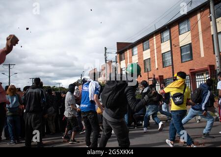 Bogota, Kolumbien. Juni 2021. Ein Demonstrator wirft der kolumbianischen Bereitschaftspolizei (ESMAD) Steine und Debree zu, als die Bewohner von Fontanar - Suba in Bogota, Kolumbien, protestierten und gegen die kolumbianische Bereitschaftspolizei (Escuadron Movil Antidisturbios ESMAD) gegen den Besuch des kolumbianischen Präsidenten Ivan Duque Marquez in einem Park, in dem Bogotas U-Bahn-System gebaut werden soll, zusammenprallten. Inmitten von zwei Monaten regierungsfeindlicher Proteste gegen den Präsidenten Ivan Duque Marquez, Ungleichheiten und Polizeiunruhen während der Proteste am 29. Juni 2021. Kredit: Long Visual Press/Alamy Live Nachrichten Stockfoto