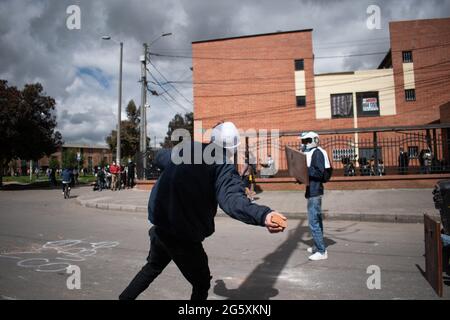 Bogota, Kolumbien. Juni 2021. Ein Demonstrator wirft der kolumbianischen Bereitschaftspolizei (ESMAD) Steine und Debree zu, als die Bewohner von Fontanar - Suba in Bogota, Kolumbien, protestierten und gegen die kolumbianische Bereitschaftspolizei (Escuadron Movil Antidisturbios ESMAD) gegen den Besuch des kolumbianischen Präsidenten Ivan Duque Marquez in einem Park, in dem Bogotas U-Bahn-System gebaut werden soll, zusammenprallten. Inmitten von zwei Monaten regierungsfeindlicher Proteste gegen den Präsidenten Ivan Duque Marquez, Ungleichheiten und Polizeiunruhen während der Proteste am 29. Juni 2021. Kredit: Long Visual Press/Alamy Live Nachrichten Stockfoto