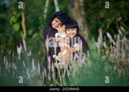 Zwei niedliche kleine Mädchen spielen mit Kätzchen an schönen sonnigen Tag im Park Stockfoto