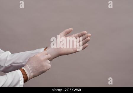 Der Arzt zieht Einweg-Gummischutzhandschuhe an. Stockfoto