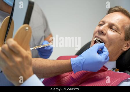 Fragmentfoto eines Mannes mittleren Alters, der in der Klinik Zähne aufhellt Stockfoto