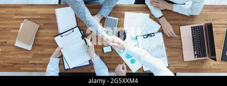 Geschäftsleute an ihrem Schreibtisch schütteln sich die Hände im Händedruck Stockfoto