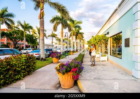 Naples, USA - 29. April 2018: Palmen auf der Straße in Florida Downtown Beach City Town während des Sonnenuntergangs mit Sonnenlicht und Menschen auf Bürgersteigen Stockfoto