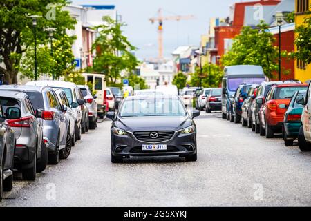 Reykjavik, Island - 19. Juni 2018: Innenstadt-Straße in der Innenstadt mit Autofahren im Verkehr und Hintergrund von geparkten Fahrzeugen und con Stockfoto