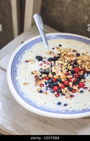 Schale mit blauem Nationalmuster mit Quark und Joghurt-Smoothie mit Chia, Himbeeren, roten Johannisbeeren, Heidelbeeren, Brombeeren, Walnüssen auf einem Stockfoto