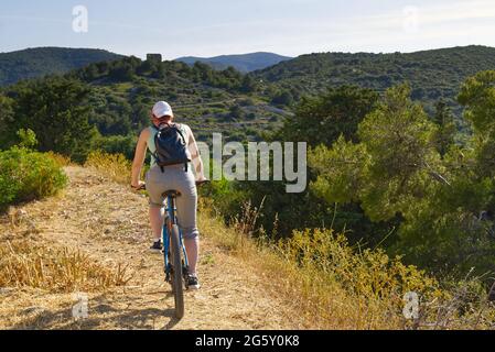 Eine Radfahrerin fährt an einem sonnigen Sommertag auf einem Bergweg mit ihrem Mountainbike. Stockfoto