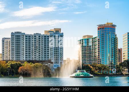 Orlando, USA - 16. Januar 2021: Blick auf die Skyline von Florida im Lake Eola Park in der Innenstadt mit Wasserbrunnen und Sonnenaufgang in den städtischen Wolkenkratzern Stockfoto