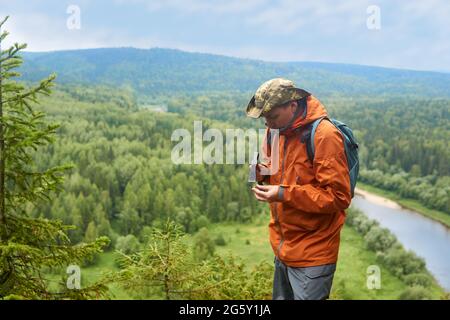 Männlicher Geologe auf einer Expedition untersucht einen Stein mit einem Hammer auf Härte Stockfoto