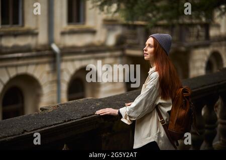 Hübsche Rothaarige Frau im Mantel auf der Suche nach einem schönen historischen Ort, sich umsehen, in Kontemplation stehen, neue Gegend erkunden, genießen junge Reisende Stockfoto