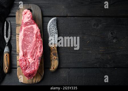 Scotch Filet Ganzschnitt, marmoriertes Rindfleisch Rib Eye Top Choice Fleischset, auf schwarzem Holztisch-Hintergrund, Draufsicht flach liegend, mit Platz für Text Stockfoto