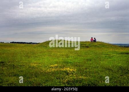 OLD WINCHESTER HILL, ENGLAND - 26. JUNI 2021: Zwei Frauen machen im Sommer ein Picknick auf einem Tumulus auf Old Winchester Hill, Hampshire Stockfoto