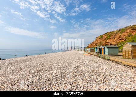 Kiesstrand und bunte Hütten unter Klippen in Budleigh Salterton, einer malerischen, unberührten kleinen Stadt an der Jurassischen Küste in East Devon, Südwestengland Stockfoto