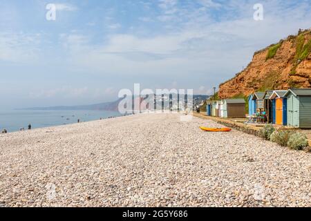 Kiesstrand und bunte Hütten unter Klippen in Budleigh Salterton, einer malerischen, unberührten kleinen Stadt an der Jurassischen Küste in East Devon, Südwestengland Stockfoto