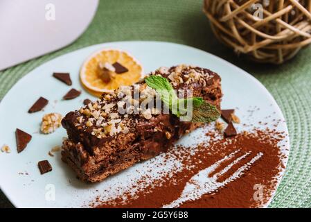 Süßes Frühstück mit Schokoladenhonig-Kekskuchen mit saurer und Buttercreme und Walnüssen, einer Scheibe getrockneter Orange und mit Minzblatt und coc verziert Stockfoto