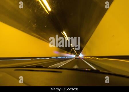 Blick aus einer Windschutzscheibe während der Fahrt durch Tunnel mit Verschwommenes Licht Stockfoto