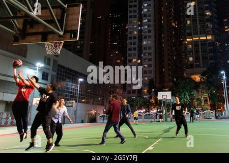 In Hongkong wird nachts auf einem Tennisplatz im Stadtzentrum Basketball gespielt Stockfoto