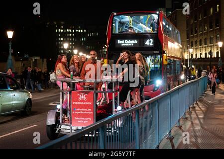 Eine Gruppe von Frauen auf einem Party-Bike in der Nacht auf einer belebten Straße in London, England Stockfoto