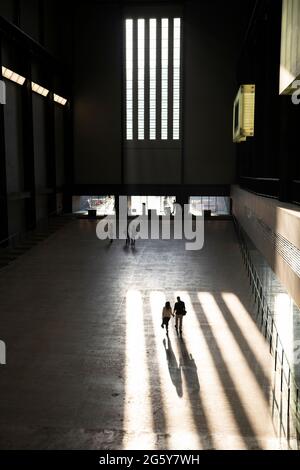 Ein Paar, das in der Tate Modern in London, Großbritannien, durch einen Lichtwellenstreich läuft Stockfoto