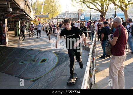 Jungs machen Stunts auf Fahrrädern, während Touristen im Southbank Skate Space in London, Großbritannien, zusehen Stockfoto