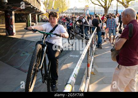 Jungs machen Stunts auf Fahrrädern, während Touristen im Southbank Skate Space in London, Großbritannien, zusehen Stockfoto