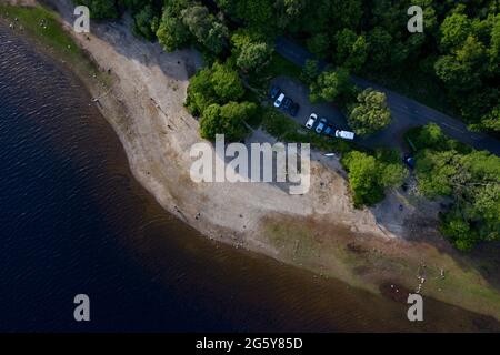 Loch Venachar, Loch. Lomonnd und Trossachs National Park, Schottland, Großbritannien. 30. Juni 2021. IM BILD: Eine Weitwinkelansicht des Kies- und Steinstrandes am Loch Venachar, der normalerweise unter ein paar Fuß Wasser liegt, ist aufgrund der schwindenden Wasserversorgung, die aufgebraucht ist, freigelegt. An diesem Teil des loch sollte es keinen Strand geben, aber man kann sehen, wie die Leute diesen Make Shift-Strand benutzen, um die Abendsonne zu genießen. Quelle: Colin Fisher/Alamy Live News Stockfoto