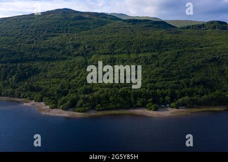 Loch Venachar, Loch. Lomonnd und Trossachs National Park, Schottland, Großbritannien. 30. Juni 2021. IM BILD: Eine Weitwinkelansicht des Kies- und Steinstrandes am Loch Venachar, der normalerweise unter ein paar Fuß Wasser liegt, ist aufgrund der schwindenden Wasserversorgung, die aufgebraucht ist, freigelegt. An diesem Teil des loch sollte es keinen Strand geben, aber man kann sehen, wie die Leute diesen Make Shift-Strand benutzen, um die Abendsonne zu genießen. Quelle: Colin Fisher/Alamy Live News Stockfoto