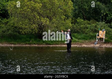 Loch Venachar, Loch. Lomonnd und Trossachs National Park, Schottland, Großbritannien. 30. Juni 2021. IM BILD: Ein schwarzer ethnischer Mann wird an einem heißen und sonnigen Abend auf dem loch gesehen, wie er seine Angelrute in den loch wirft, während er Musik über seine Kopfhörer hört. Quelle: Colin Fisher/Alamy Live News Stockfoto