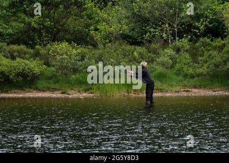 Loch Venachar, Loch. Lomonnd und Trossachs National Park, Schottland, Großbritannien. 30. Juni 2021. IM BILD: Ein schwarzer ethnischer Mann wird an einem heißen und sonnigen Abend auf dem loch gesehen, wie er seine Angelrute in den loch wirft, während er Musik über seine Kopfhörer hört. Quelle: Colin Fisher/Alamy Live News Stockfoto