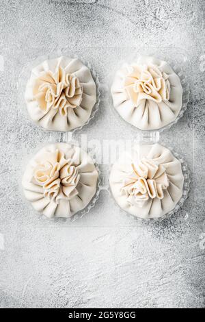 Ungekochte Baozi chinesische Knödel. Azuan-Knödel-Set, in Kunststoffschale, auf grauem Steingrund, Draufsicht flach liegend, mit Platz für Text Stockfoto