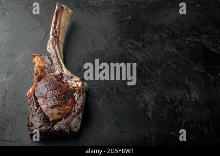 Steak auf dem Knochen. tomahawk Steak frisch gegrillt trocken gealterte BBQ-Food-Set, auf schwarzem Stein Hintergrund, mit Platz für Text Stockfoto