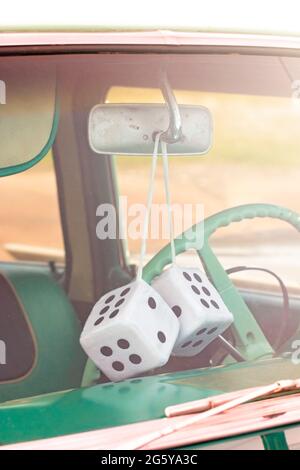 Ein Paar Fuzzy Dice, das aus dem Rückspiegel eines antiken Autos aufgehängt wird Stockfoto