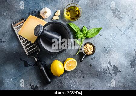 Zutaten für Pesto-Genovese-Sauce Parmesan, Basilikumblätter, Pinienkerne, Olivenöl, Knoblauch und Salz. Traditionelle italienische Küche. Auf dem Stein Stockfoto