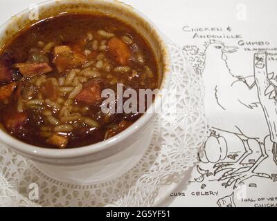 Eine Tasse Gumbo sitzt auf einem illustrierten Rezept für das Gericht. Stockfoto