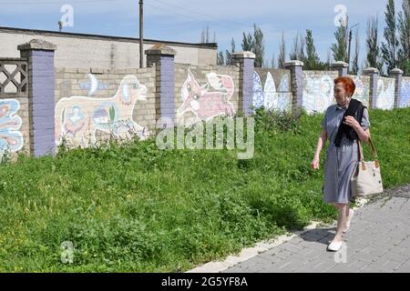 Ein Bewohner von Kramatorsk geht an den Straßenkunstgemälden im zentralen Teil der Stadt vorbei. Die Straßenkunstkultur der Ukraine ist mutig und erfrischend und zeigt den kraftvollen Geist der Jugend des Landes. Künstler verbinden sowjetische Einflüsse nahtlos mit bekannten Prüfsteinen wie der amerikanischen Hip-Hop-Kultur und dem Abstrakten Expressionismus, eine Art Verschmelzung mit manchmal nationalen Kunsttraditionen. Straßenkunstmaler in der modernen Ukraine reisen oft von West- in den Ostteil des Landes, um die Straßen der Stadt bunter und neugieriger zu machen. (Foto von Andriy Andriyenko/SOPA Images/Sipa USA) Stockfoto