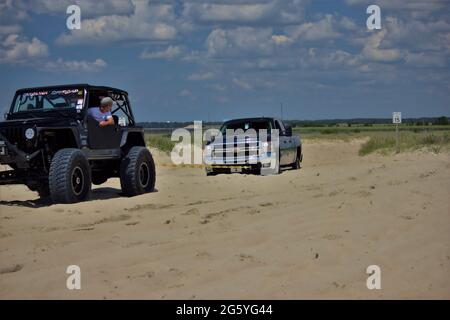 Ein Jeep, der einen Chevy Pick-up aus dem Sand am Carolina Beach, NC, zieht Stockfoto