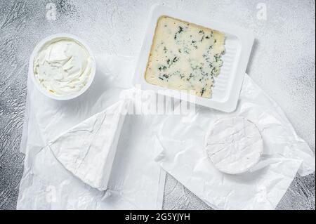 Verschiedene Käsesorten auf Küchentisch, Brie, Camembert, Gorgonzola und blauer Cremekäse. Weißer Hintergrund. Draufsicht Stockfoto