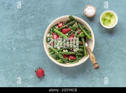 Ein gesunder und köstlicher Salat aus frischen Erdbeeren, grünem Spargel, Feta-Käse mit Gemüseblättern. Stockfoto