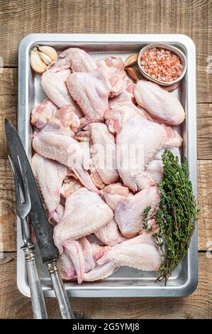 Rohe Hähnchenflügel Geflügelfleisch bereit zum Kochen mit Kräutern. Holzhintergrund. Draufsicht Stockfoto