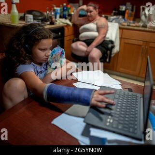 Sacramento, Kalifornien, USA. Mai 2021. Aryanna Toched, 8, hält am Freitag, 28. Mai 2021 in Sacramento ihr Stofftier in der Hand, als sie ihren Computer mit ihrem gebrochenen Arm bedient. Ihre Mutter Kristi Philips macht eine Pause, während sie Kartoffelpüree und Schweinekoteletts zum Abendessen im Residence Inn by Marriott Hotel zubereitet, in dem sie sich jetzt aufhalten. Sie hofft, eines Tages in einem Haus zu leben, aber seit einem Jahr leben sie in Hotelzimmern und einem Wohnmobil, das sie besitzen, wenn sie nicht in der Lage sind, für Hotels zu bezahlen. (Bild: © Renee C. Byer/The Sacramento Bee/ZUMA Press Wire) Stockfoto