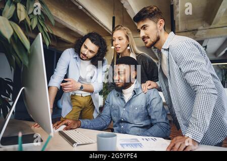 Vier multiethnische Kollegen betrachten im Büro den Computerbildschirm Stockfoto