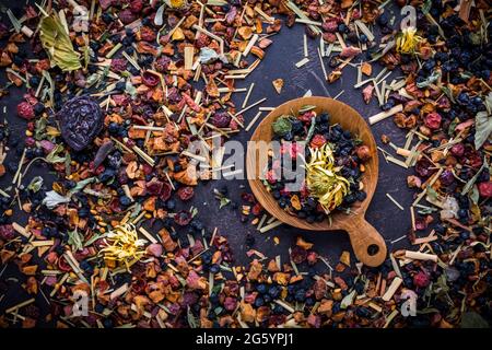 Getrocknete Teeblätter, Früchte und Beeren in Schale auf rustikalem Holztisch Stockfoto