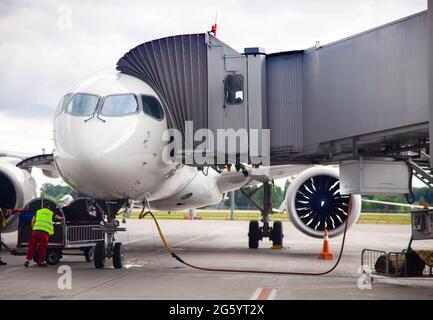 Betanken des Flugzeugs am Flughafen vor dem Abflug. Das weiße Flugzeug steht auf der Plattform, die Passagiere sitzen durch die Einstiegsbrücke. Handling-Service. Vorbereitung eines Passagierflugzeugs. Stockfoto