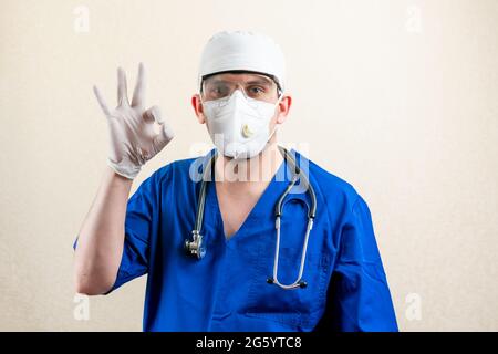 Der Arzt in Maske und Brille zeigt das Zeichen OK. Stockfoto