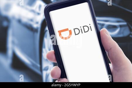 Galicia, Spanien; januar 09 2021: Hand hält ein Smartphone mit DIDI-Logo auf dem Bildschirm und verschwommene Autos auf dem Hintergrund Stockfoto