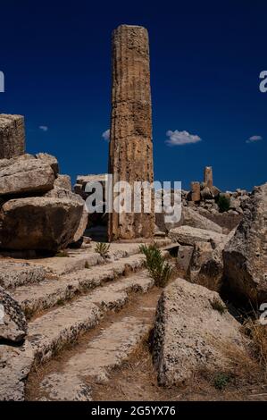 Eine einzelne, geriffelte Säule ragt zu einem tiefblauen Himmel aus den durcheinander gewirbelten Ruinen eines eingestürzten dorischen Tempels, der einst entweder der Göttin Athene oder dem gott Dionysos in der antiken griechischen Stadt und dem Hafen von Selinus oder Selinous an der Südwestküste Siziliens, Italien, geweiht war. Die Struktur, die heute als Tempel F im Selinunte Archäologischen Park erhalten ist, wurde zwischen 550 und 540 v. Chr. erbaut und wahrscheinlich bei Erdbeben im Mittelalter eingestürzt. Stockfoto