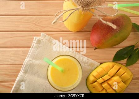 Bio-Mangosaft aus Glas und Flasche zusammen mit Obst auf Holztisch. Draufsicht. Stockfoto