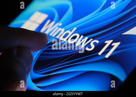 Windows 11-Logo auf dem Bildschirm des Tablets und Benutzer mit dem Finger auf sie zu sehen. Stafford, Großbritannien, 1. Juli 2021 Stockfoto