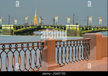 St. Petersburg, Russland, 17. Januar 2021: Beleuchtete Palastbrücke über den Fluss Neva gegen den Turm der St. Peter und Paul Kathedrale an einem Winterabend Stockfoto